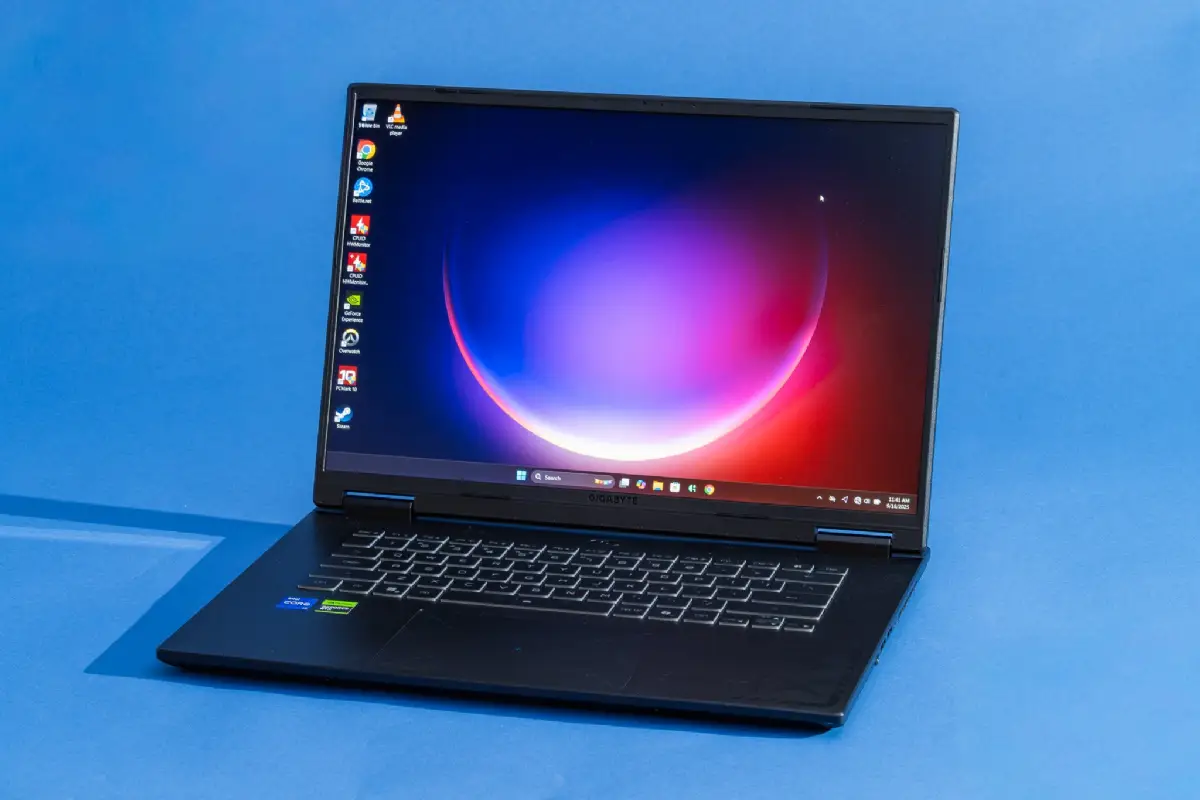 Three budget gaming laptops open on desk showing vibrant game screens and RGB keyboards