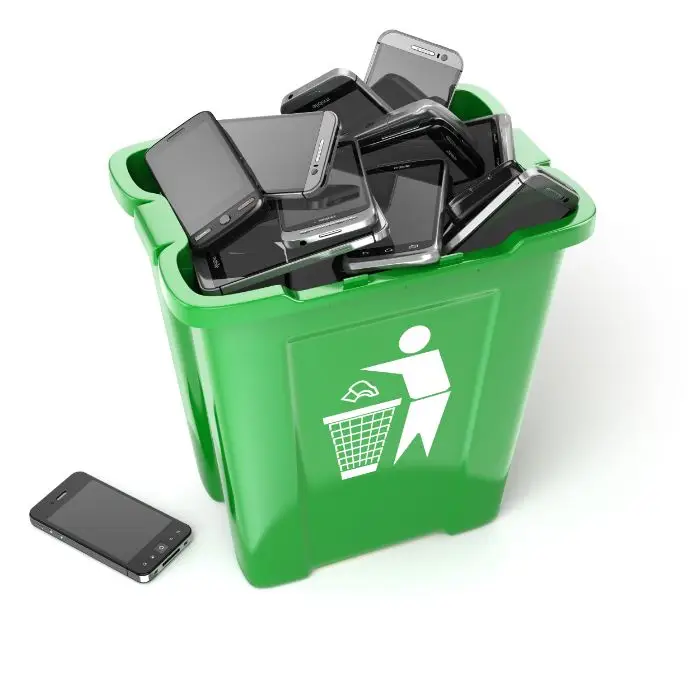 Overflowing green recycling bin filled with discarded smartphones and old mobile devices, highlighting improper electron
