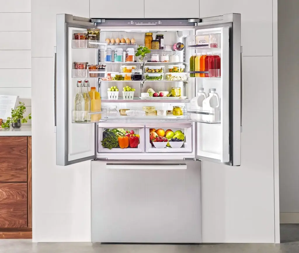 Fully stocked French door refrigerator with fresh fruits vegetables dairy organized shelves